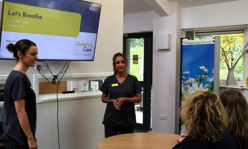 Physiotherapists, Charlotte and Nicole stood either side of a big screen with the opening slide of our 'Let's Breathe' session, chatting to attendees